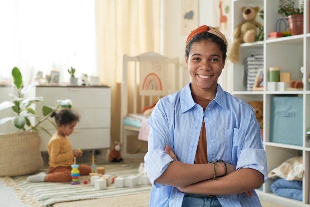 smiling-woman-in-nursery-with-child-playing-in-bac-2025-03-18-22-19-28-utc (1)